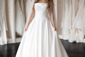 a woman in a wedding dress standing in front of a rack of dresses