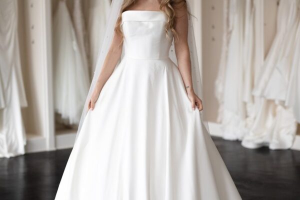 a woman in a wedding dress standing in front of a rack of dresses